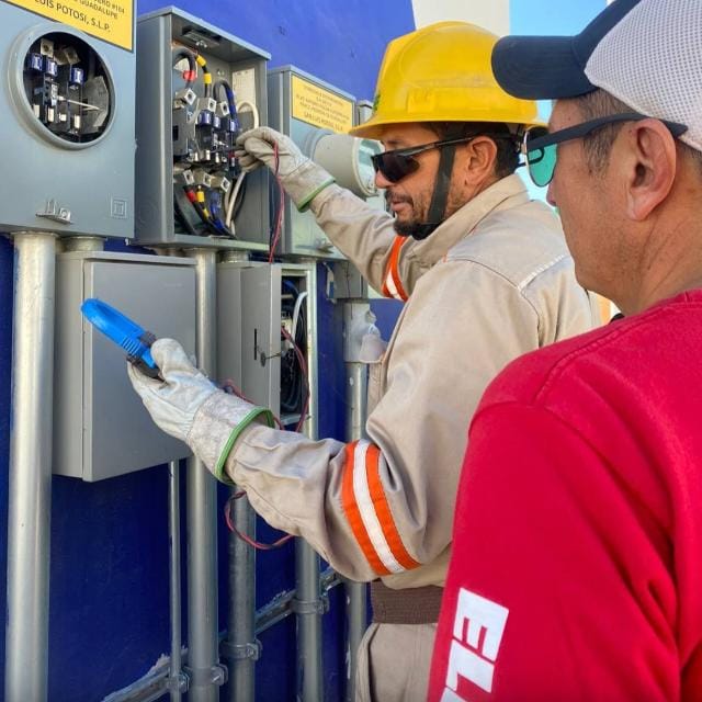 Técnico eléctrico trabajando en un panel de control con equipo de protección.