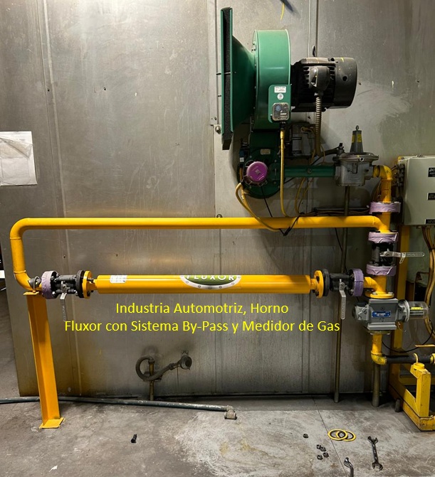 Ingeniero con casco amarillo inspecciona una gran tubería de gas en una planta industrial.