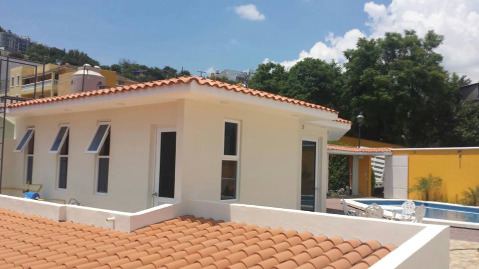 Ventanas de proyección aluminio tono blanco y cristal azul.