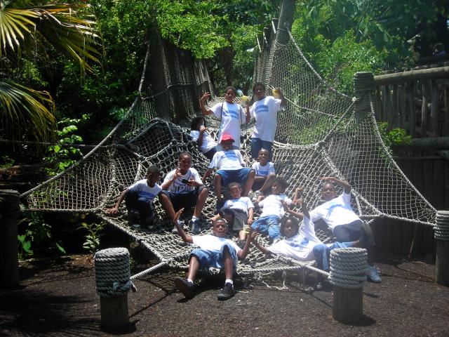 Two people wearing glasses, smiling and facing each other in a bright, modern workspace with others working in the background.
