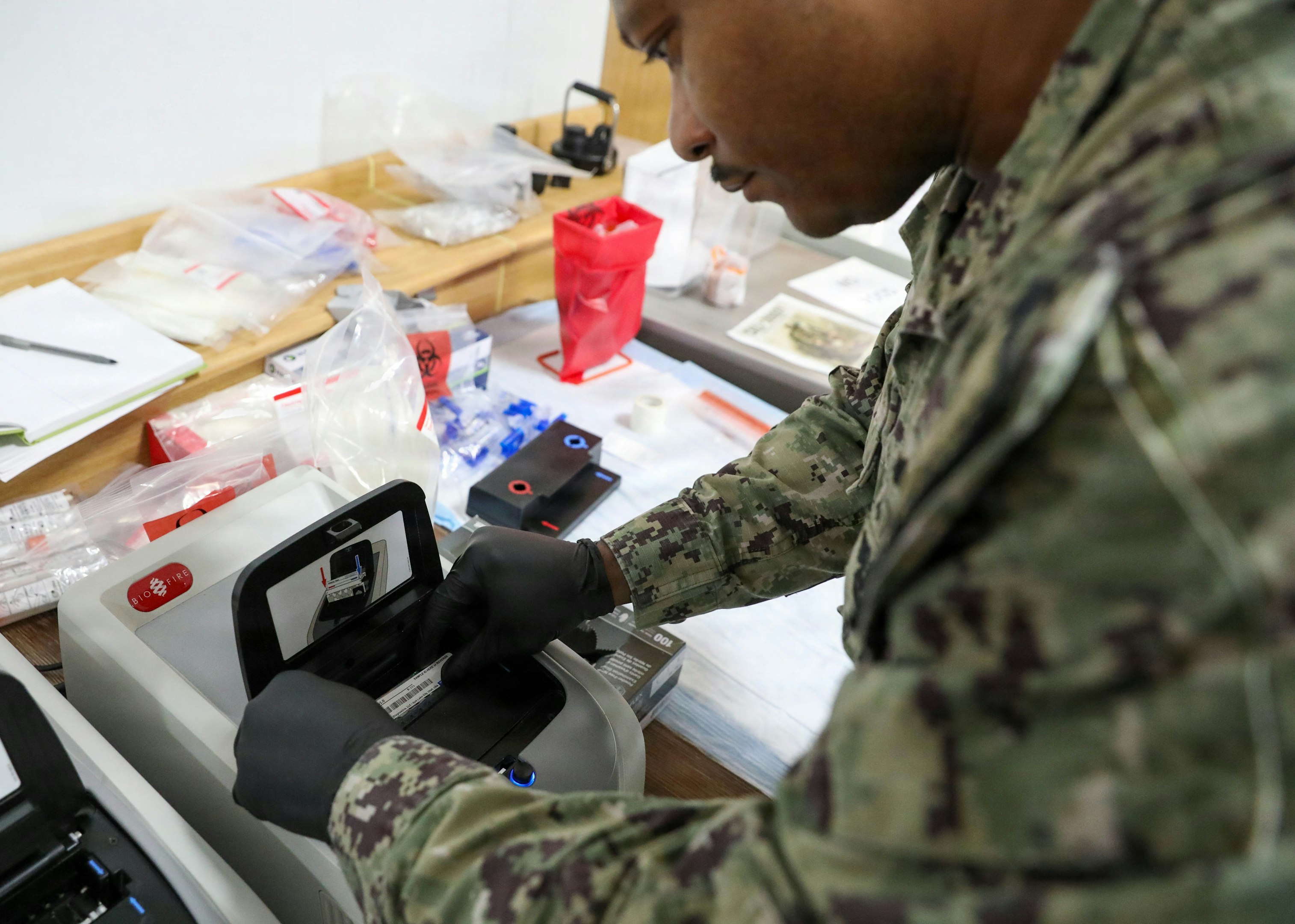 A person in uniform operates a medical testing device