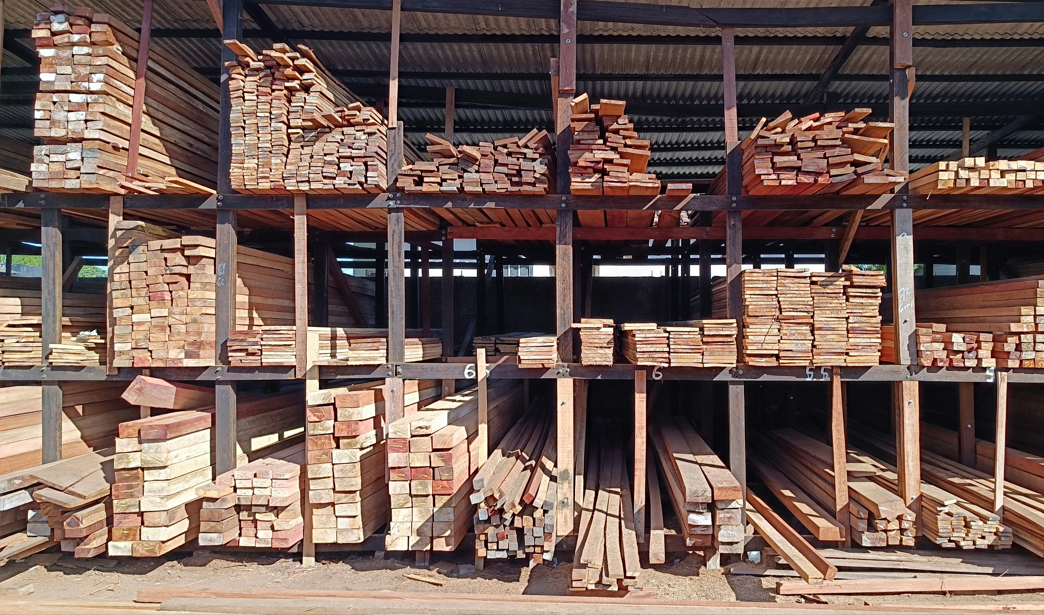 Interior de almacén industrial con trabajador supervisando áreas de carga y paletas, rodeado de cajas y estructuras metálicas.