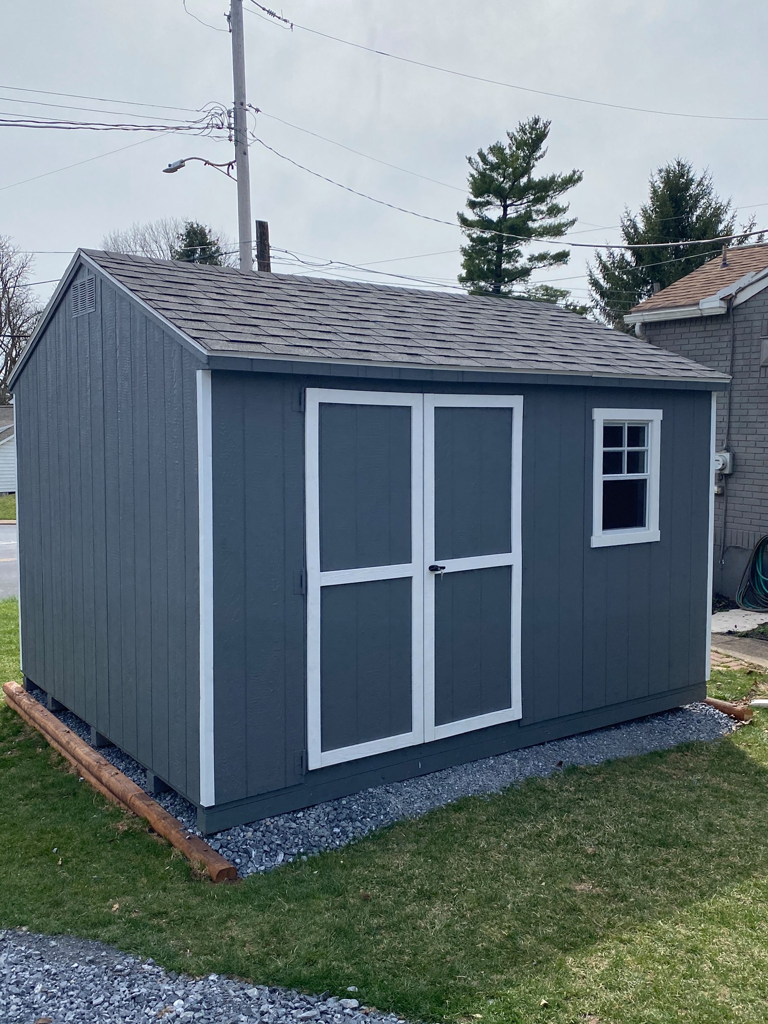10 x 12 Budget A-frame                                  
                                                              
Featuring gray colored wood siding, white trim, and black colored 30 year architectural shingles (with tarpaper underlayment), standard features included gable vents, 4’6” wide double doors in 10x10 and 10x12’s,and pressure treated floor joists.
