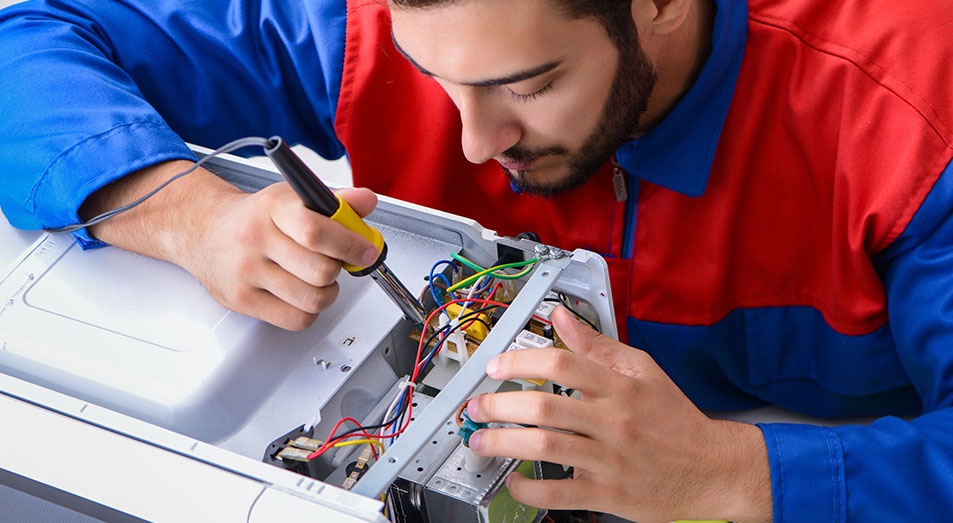 Young Repairman Fixing And Repairing Microwave Oven