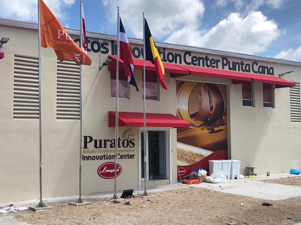 Entrada del centro de innovación Puratos en Punta Cana con banderas ondeando.