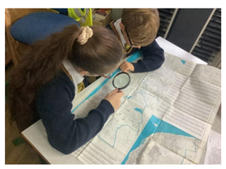 Children at Churchtown Primary School use magnifying glasses to look for Blackpool landmarks on a vintage map