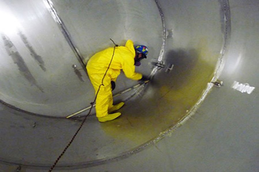 Técnicos industriales con cascos y chalecos revisan maquinaria, tuberías y paneles de control en planta moderna con montañas al fondo