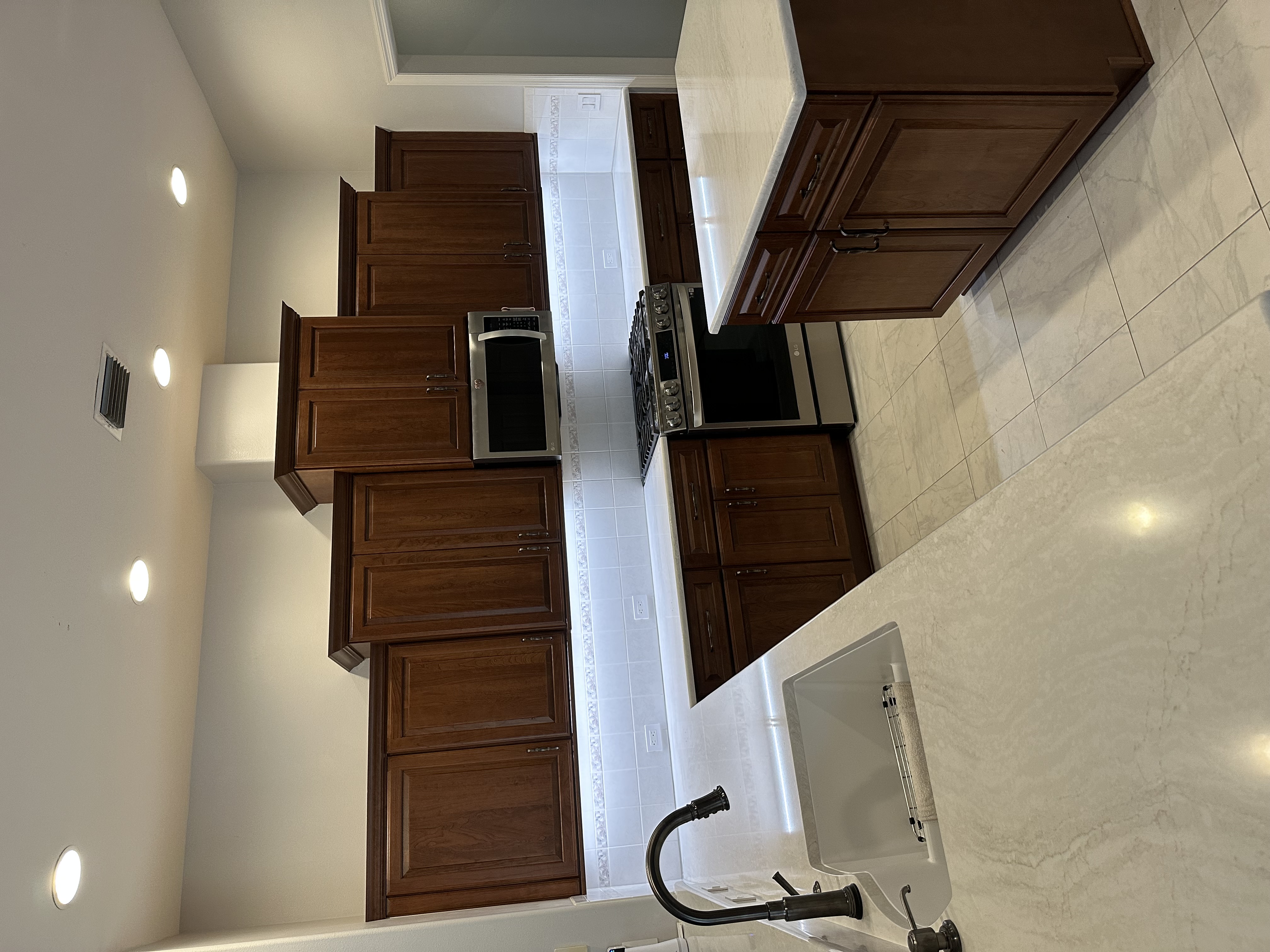 Elegant kitchen featuring semi-custom cherry door-style cabinetry with raised center panels 
in a rich Amaretto stain, complemented by sleek quartz countertops, and brushed pewter hardware.
