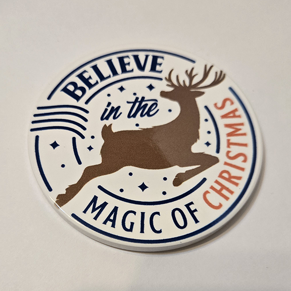 Round ceramic coaster with a believe in the magic of Christmas design