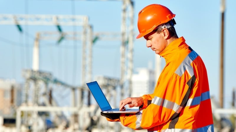 Ingeniero con casco y chaleco de seguridad usando una computadora portátil en una planta industrial. Ingeniero con casco y chaleco de seguridad usando una computadora portátil en una planta industrial.