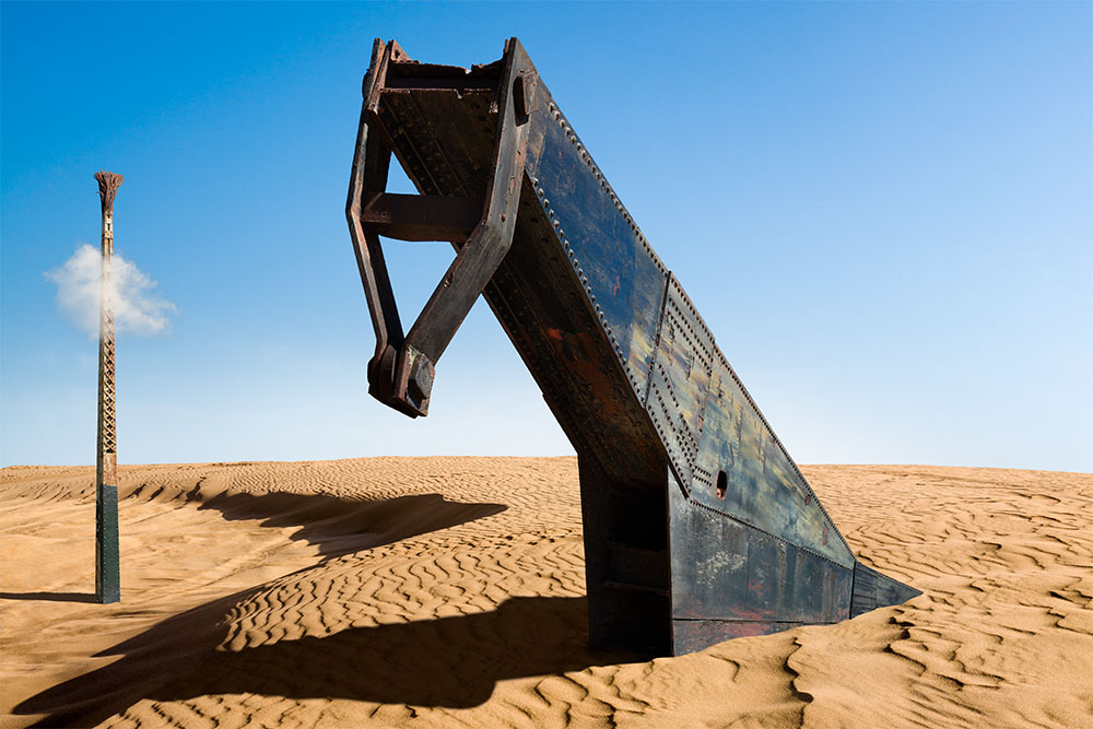 Dali inspired photo-illustration of a giant metal structure resembling a horse's head, protruding up from a desert landscape.