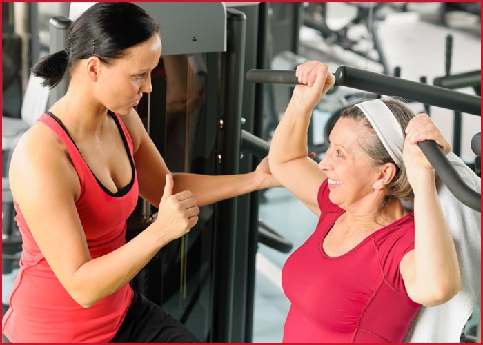 Trainer assisting woman at gym