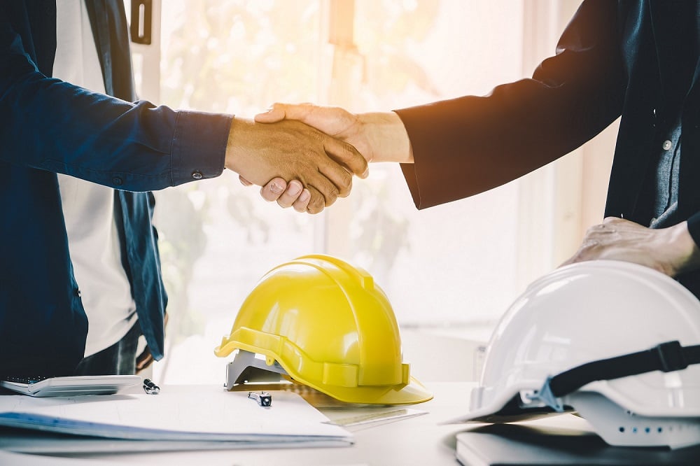 Shaking hands over hard hat