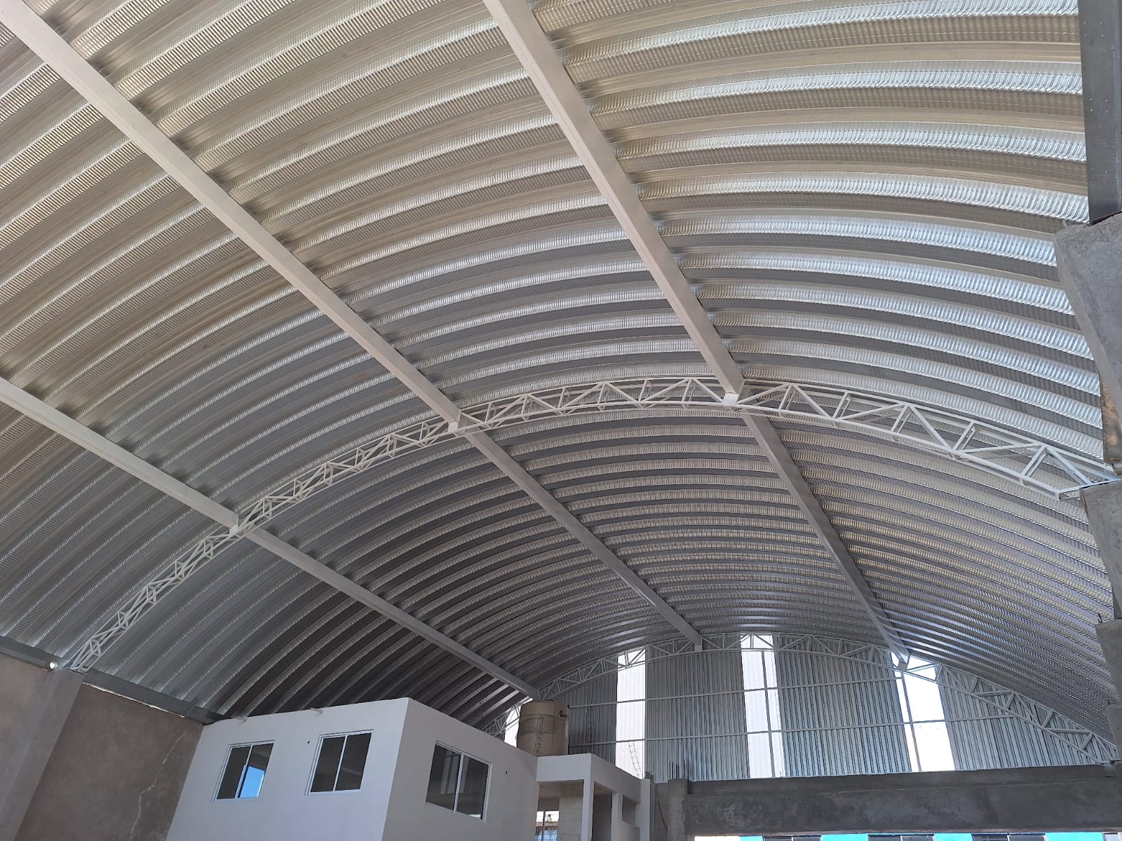 Estructura metálica azul de un edificio industrial en construcción, cielo azul de fondo.