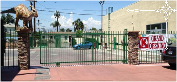 Green iron fence with stone pillars and a rolling gate.