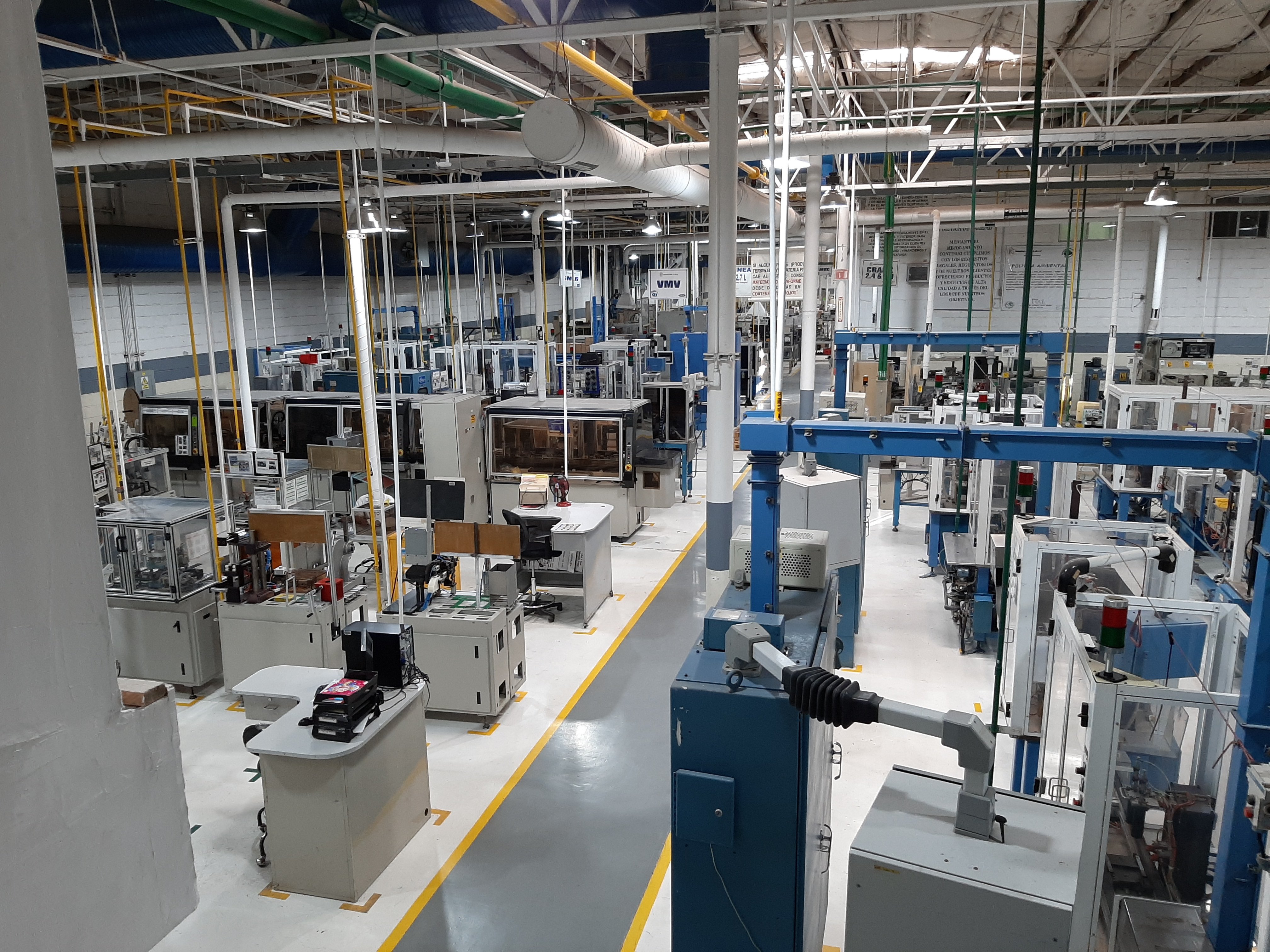 Interior de una fábrica moderna con equipos industriales y maquinaria automatizada.