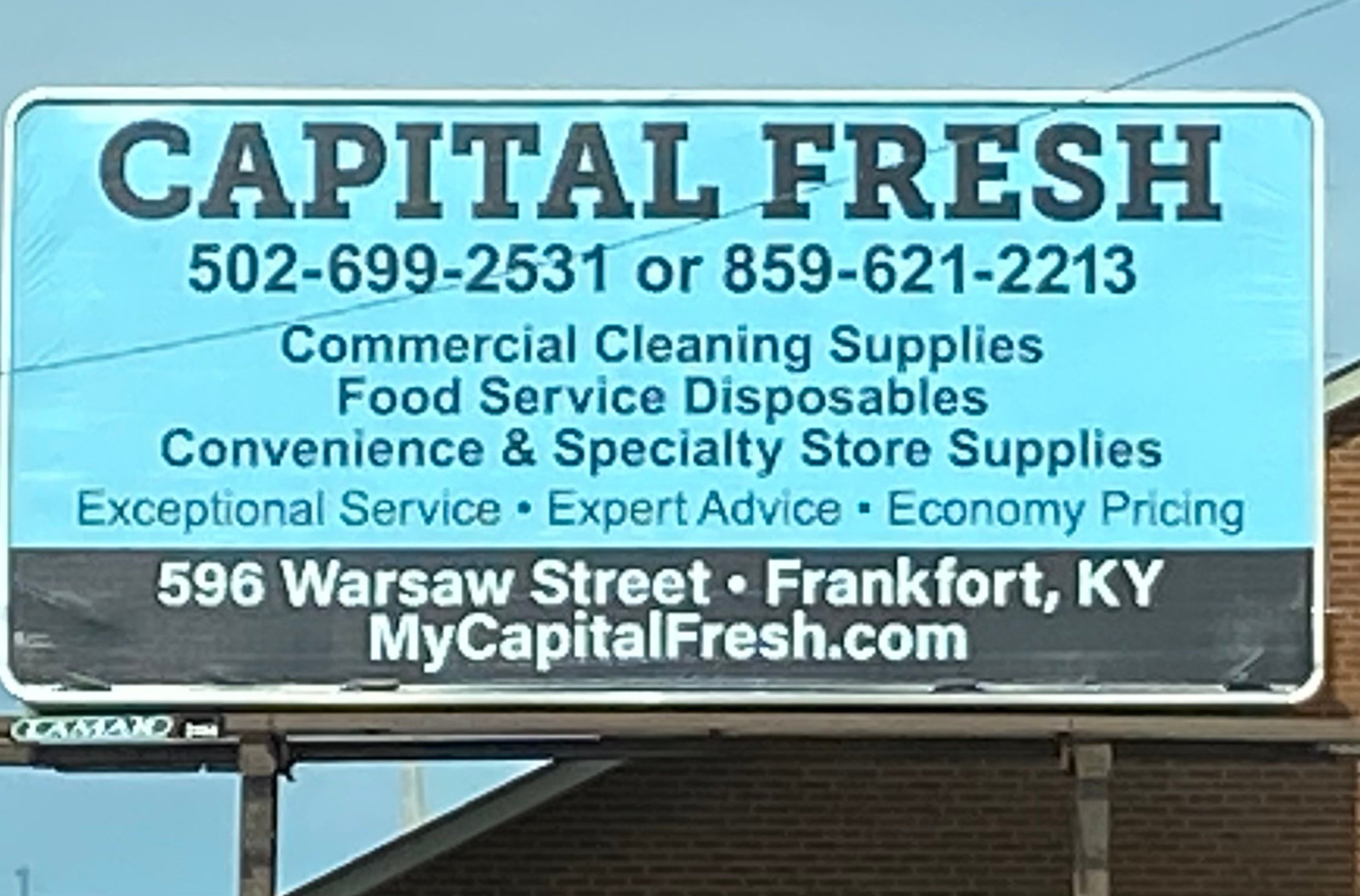 Billboard for Capital Fresh featuring contact numbers, services in commercial cleaning supplies, food service disposables, store location at 596 Warsaw Street, Frankfort, KY, and website MyCapitalFresh.com.