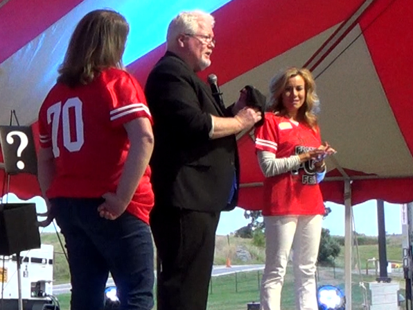 Chuck performing with two volunteers on the outdoor stage under the big top.
