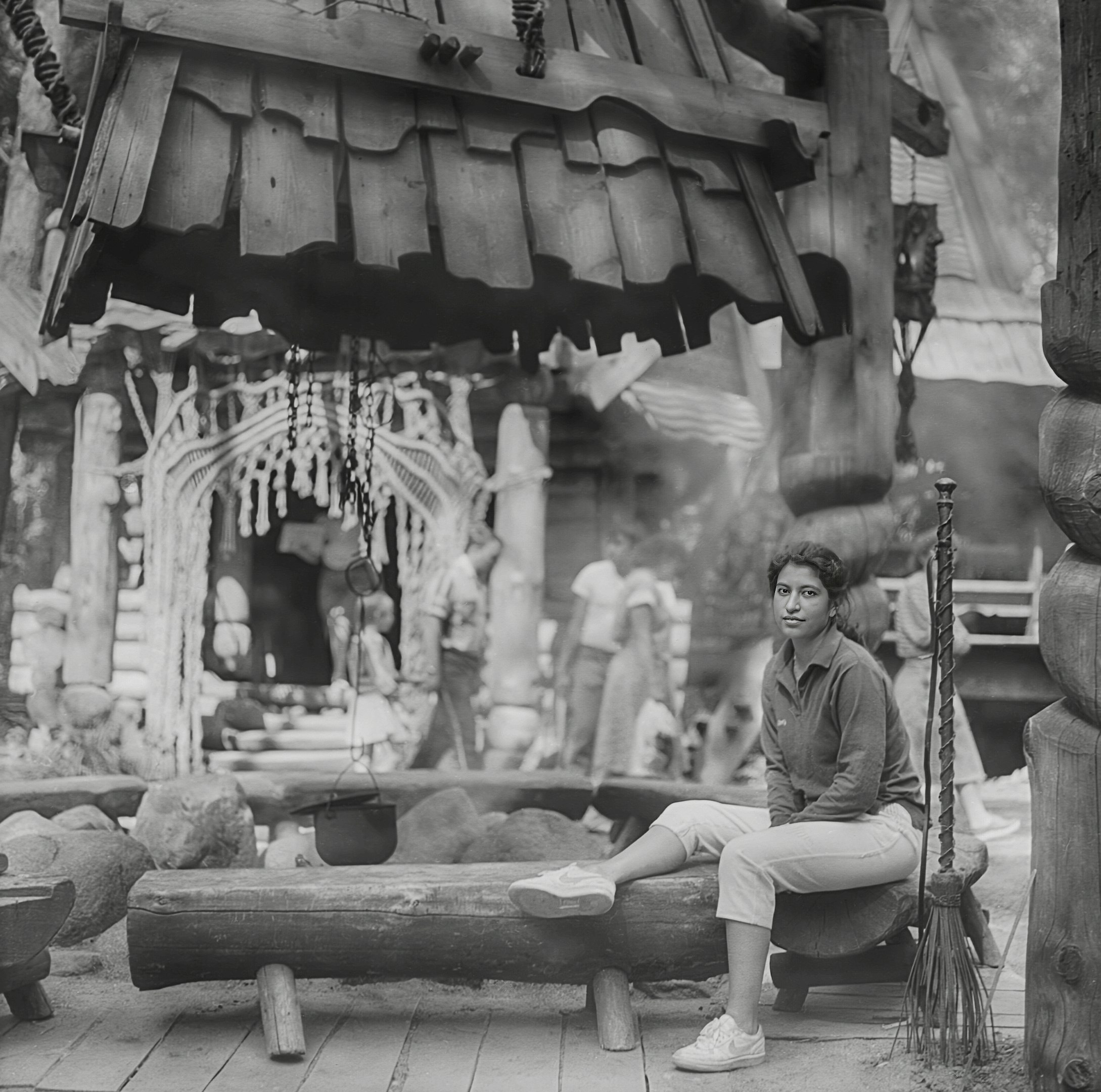 A woman sits on a bench in a market.