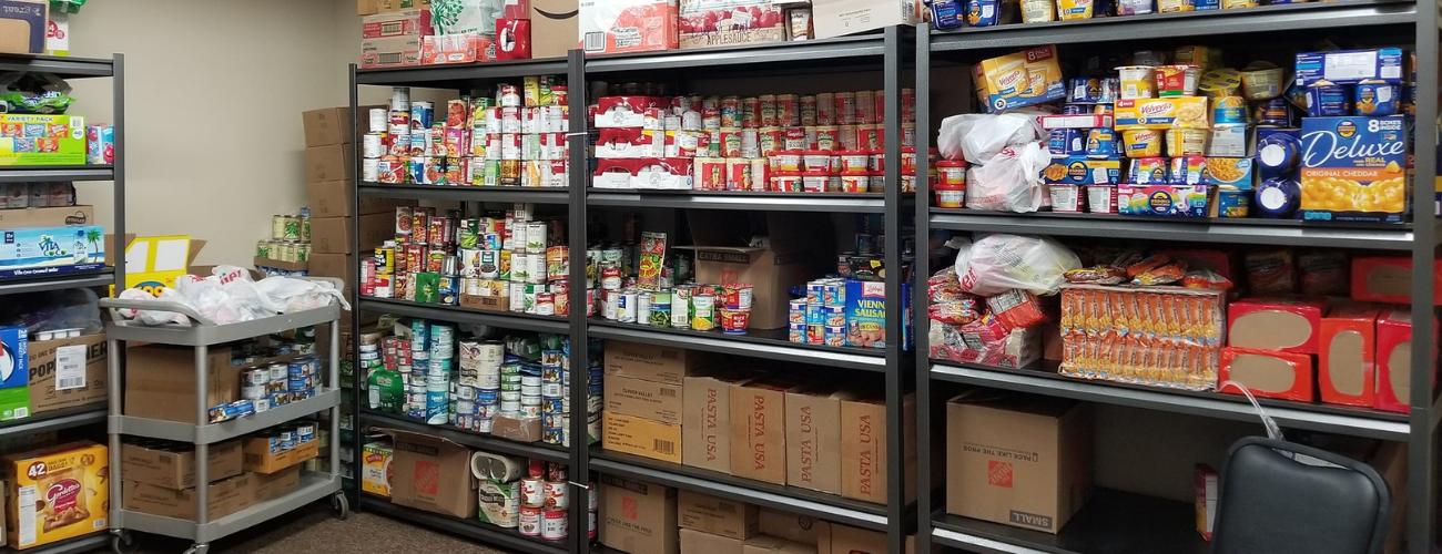Stocked food pantry with shelves of canned goods, packaged foods, and boxes; organized storage area.