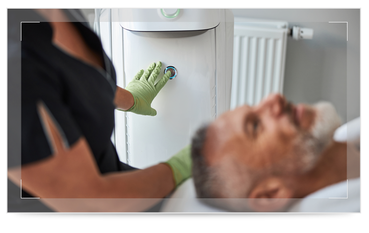 A man laying on a table with a medical worker sitting by his head A man laying on a table with a medical worker sitting by his head