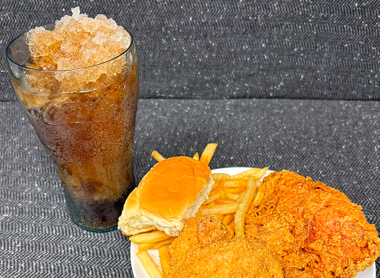 A combo meal with food on a plate and a drink beside it