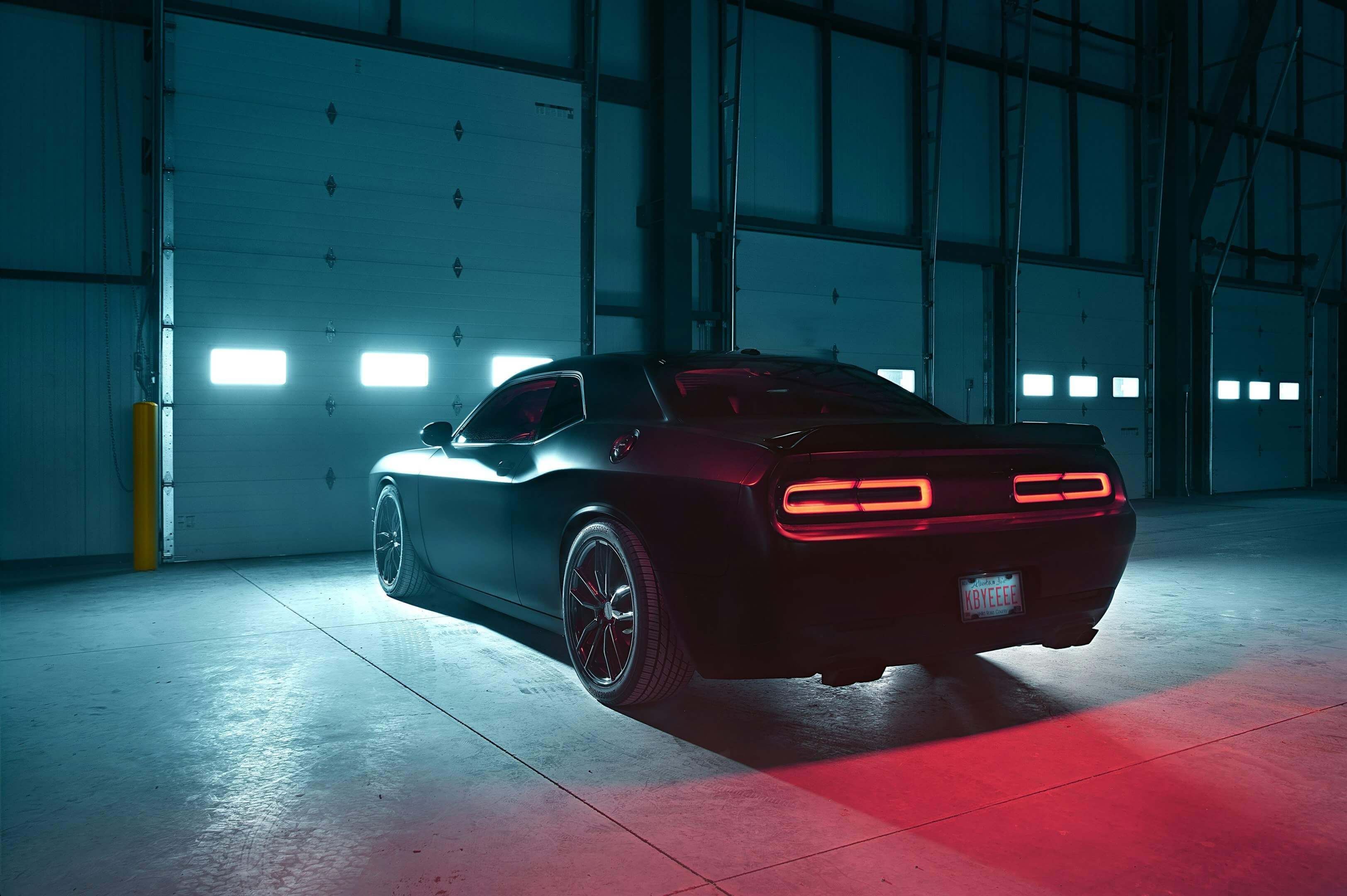 a black challenger in front of a garage