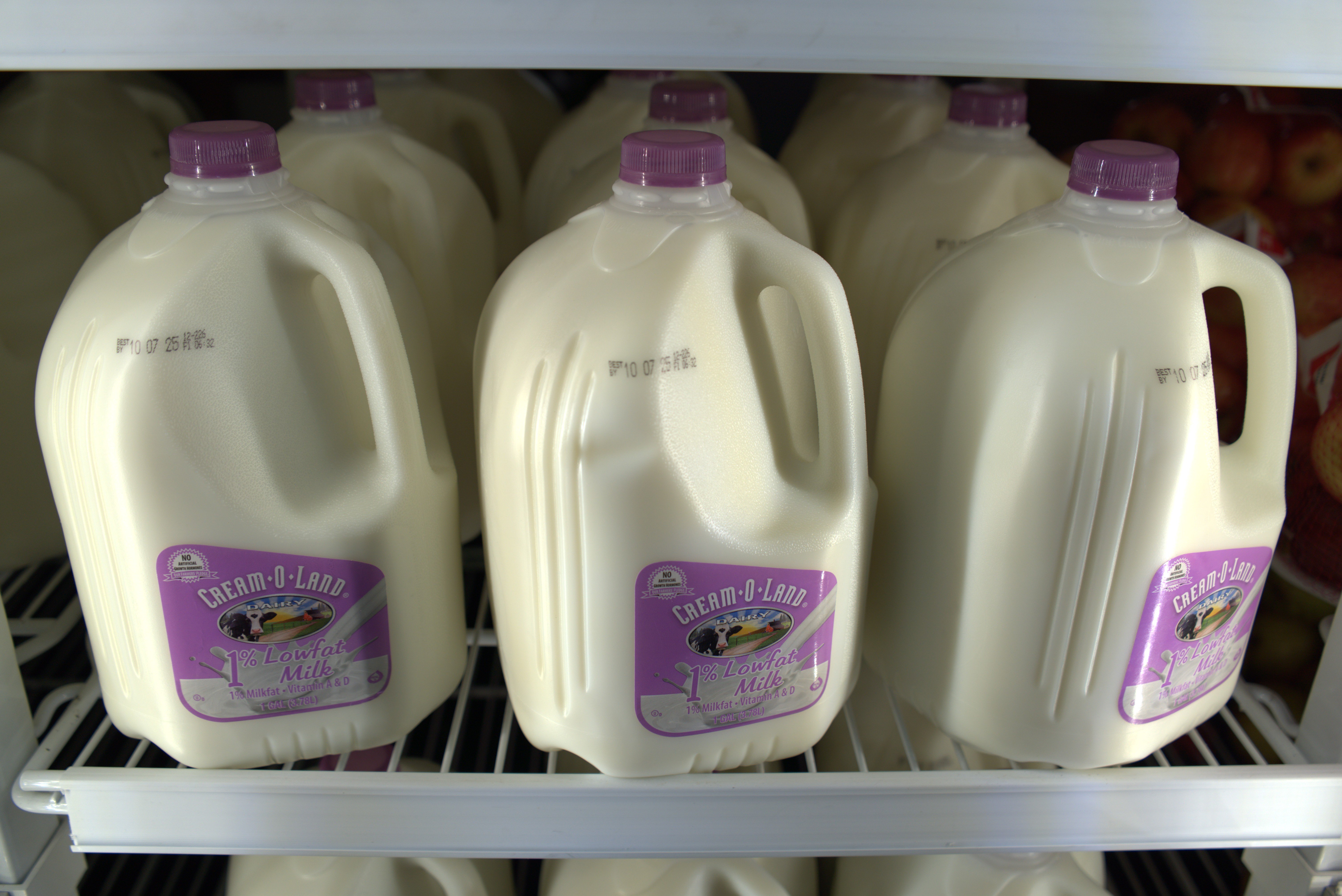 Plate of fresh strawberries, glass of milk with straws, and bag of grains on a wooden table in a grocery store.