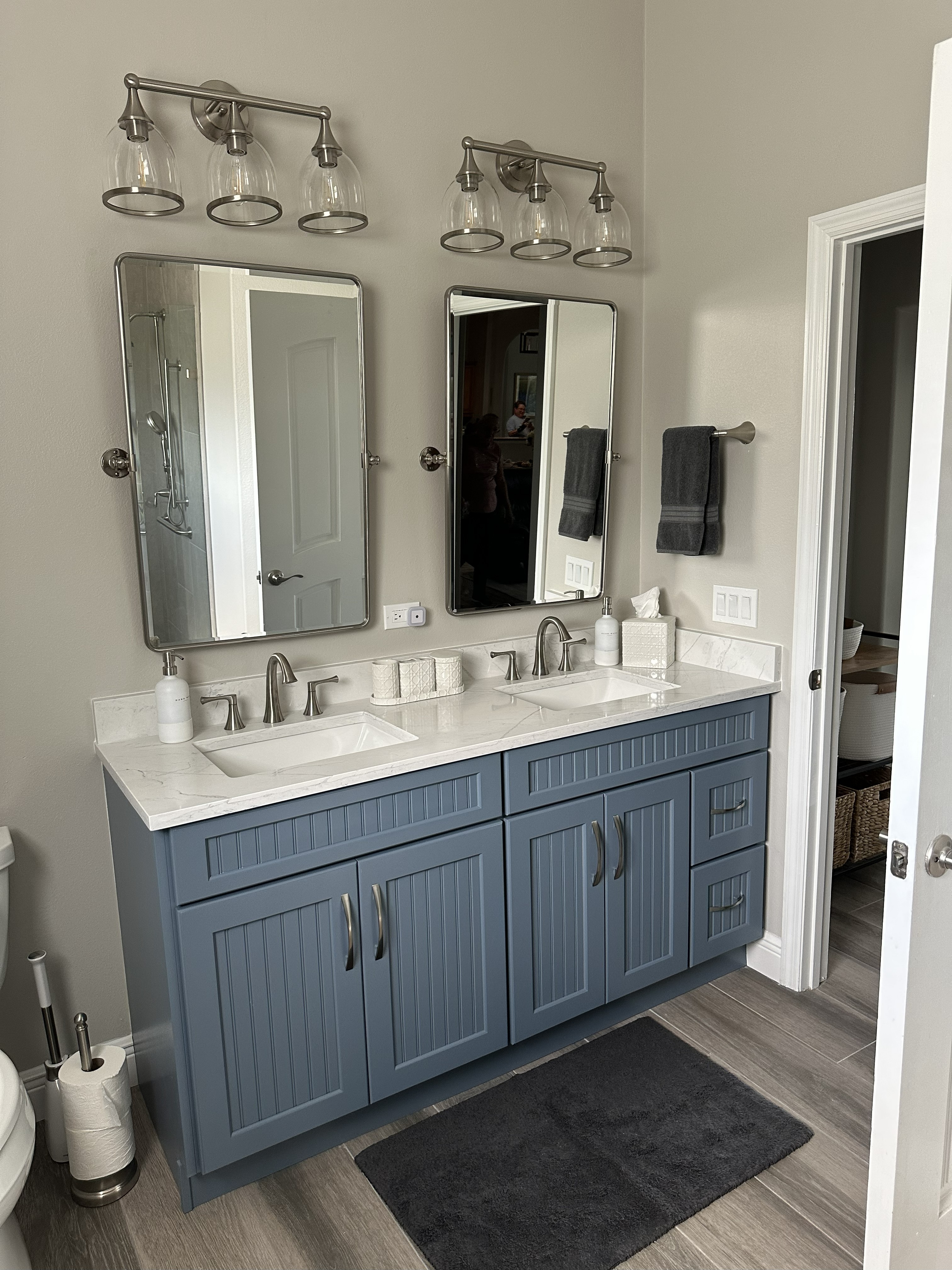 Gorgeous vanity featuring semi-custom painted beadboard cabinetry, dual sinks, Pompeii quartz surfaces, satin nickel hardware, and fixtures.