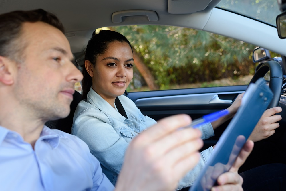 Driving instructor showing young woman notes on clipboard