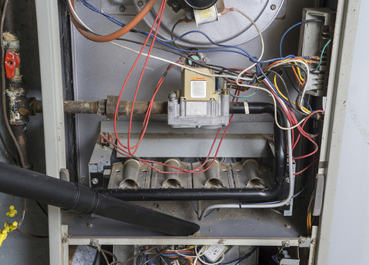 Repairman Vacuuming Inside of a Gas Furnace Repairman Vacuuming Inside of a Gas Furnace