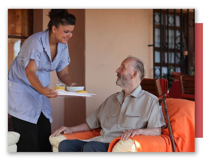  Helper in Residential Home Giving Food to Senior Man