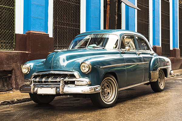 old blue green classic car in front of blue building in havana cuba