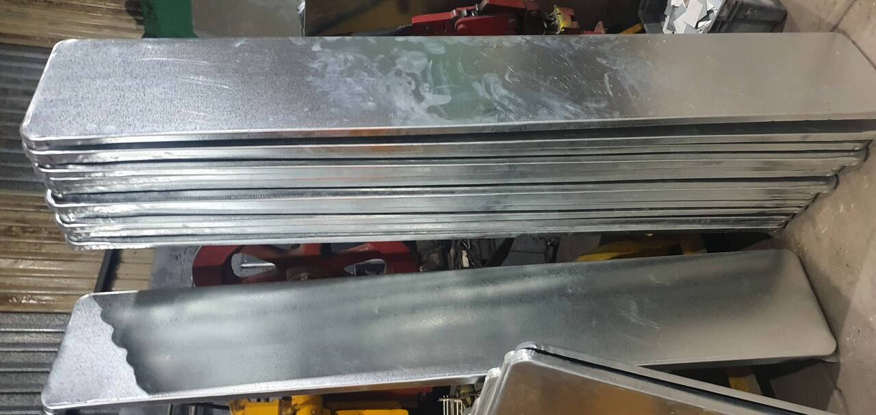 Stack of large, shiny metal sheets standing vertically in an industrial setting.
