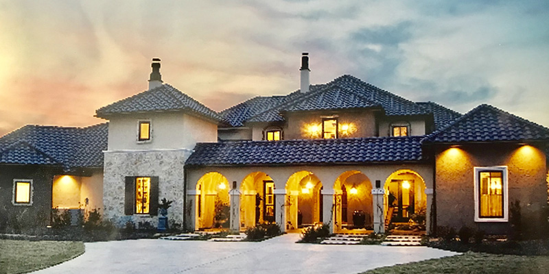 A photo of a home in the evening with several outdoor lights on