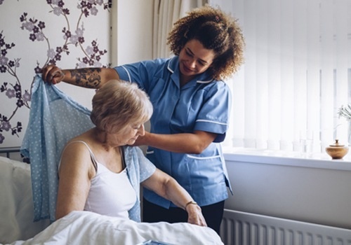 Nurse Making Notes During Home Visit With Senior Couple