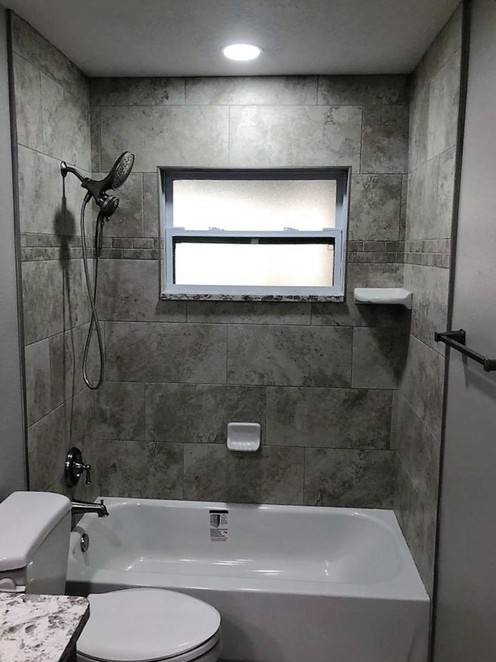 Beautifully tiled tub/shower combo with soap dish and corner shelf with satin nickel fixtures.