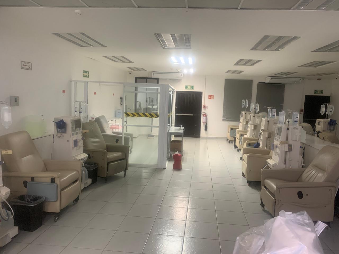Sala de hemodiálisis vacía con sillas reclinables y máquinas de diálisis alineadas.