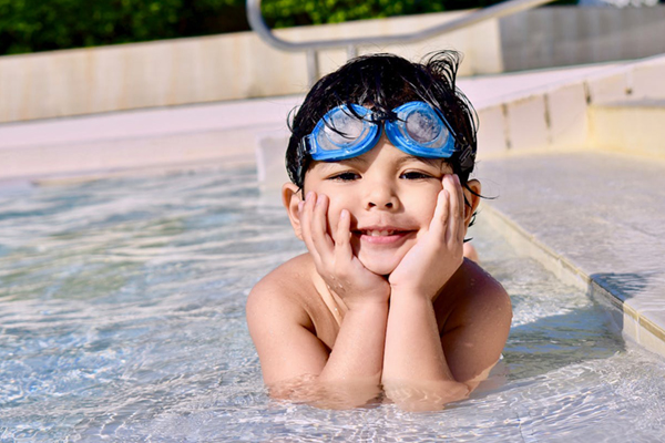 Little Boy Swims in a Swimming Pool