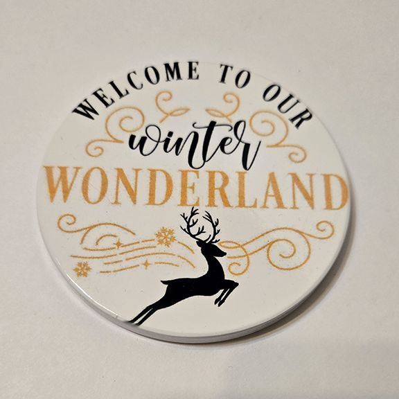 Round ceramic coaster with welcome to our winter wonderland design