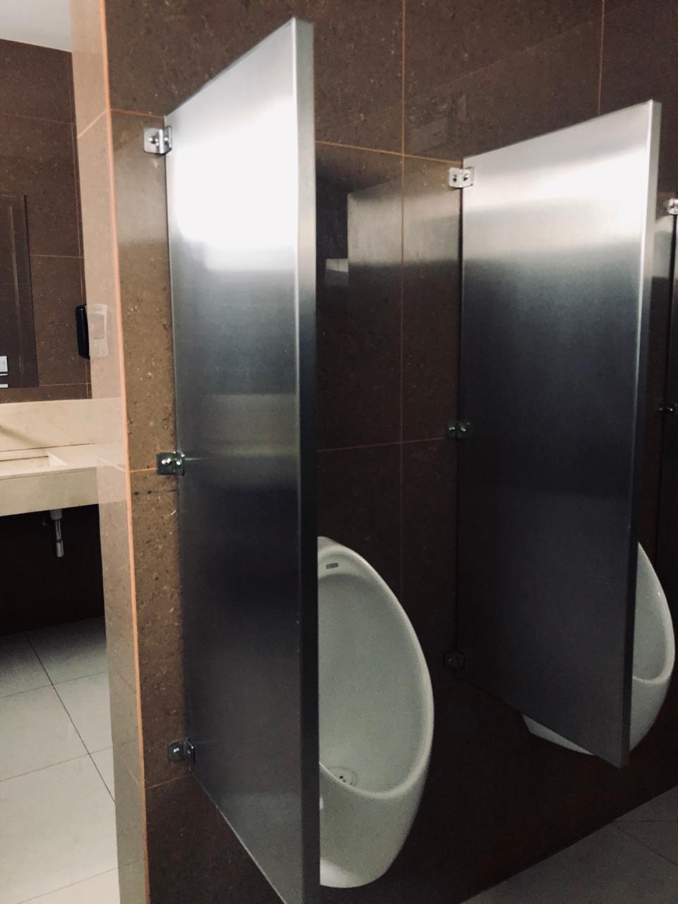 Interior de edificio moderno con ventanas grandes, plantas en macetas y vista a la ciudad.
