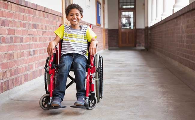 Cute Disabled Pupil Smiling At Camera In Hall