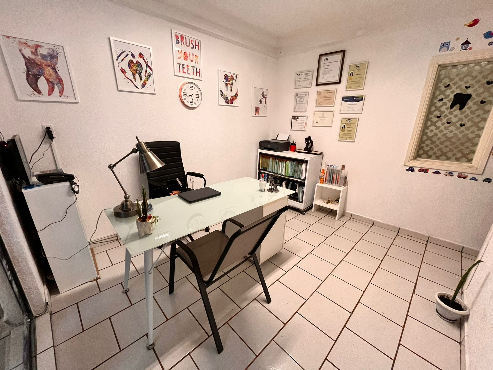 Oficina moderna con recepción y plantas decorativas, iluminación suave y grandes ventanas.