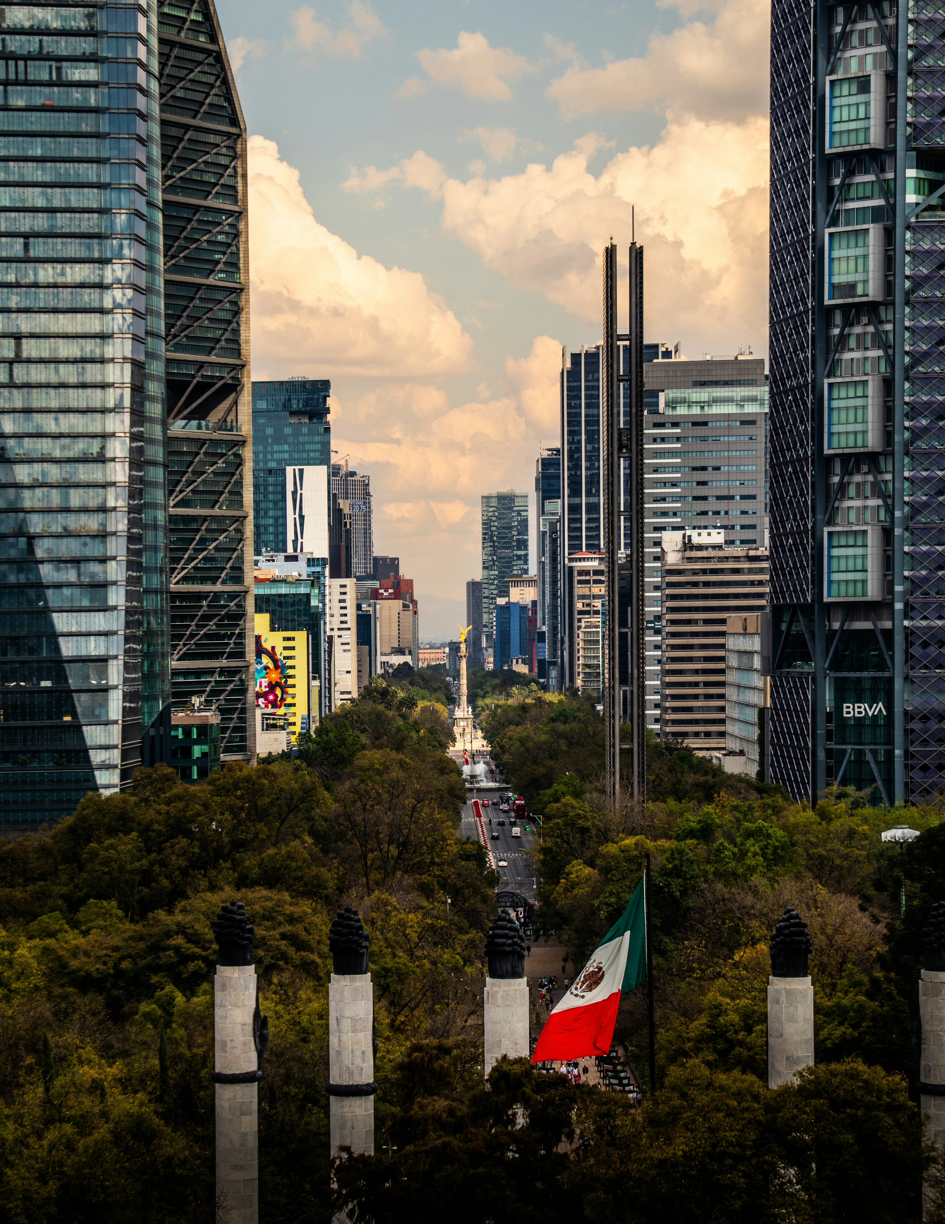 Vista panorámica de Paseo de la Reforma en Ciudad de México con modernos rascacielos, el Ángel de la Independencia y la bandera de México ondeando. Vista panorámica de Paseo de la Reforma en Ciudad de México con modernos rascacielos, el Ángel de la Independencia y la bandera de México ondeando.