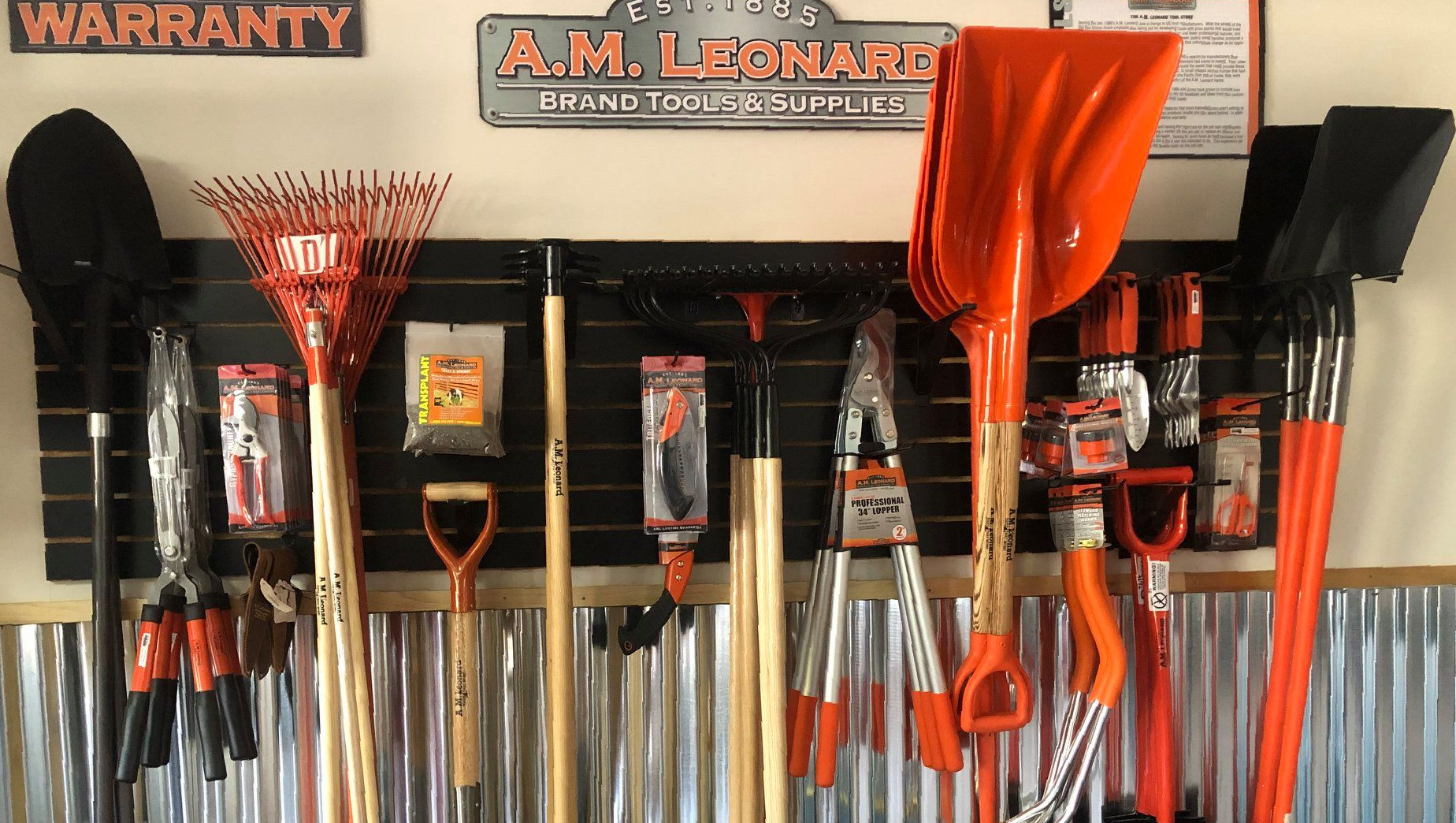 Modern sunroom with large windows and potted plants on a sunny day, featuring a wooden bench and lush green surroundings.