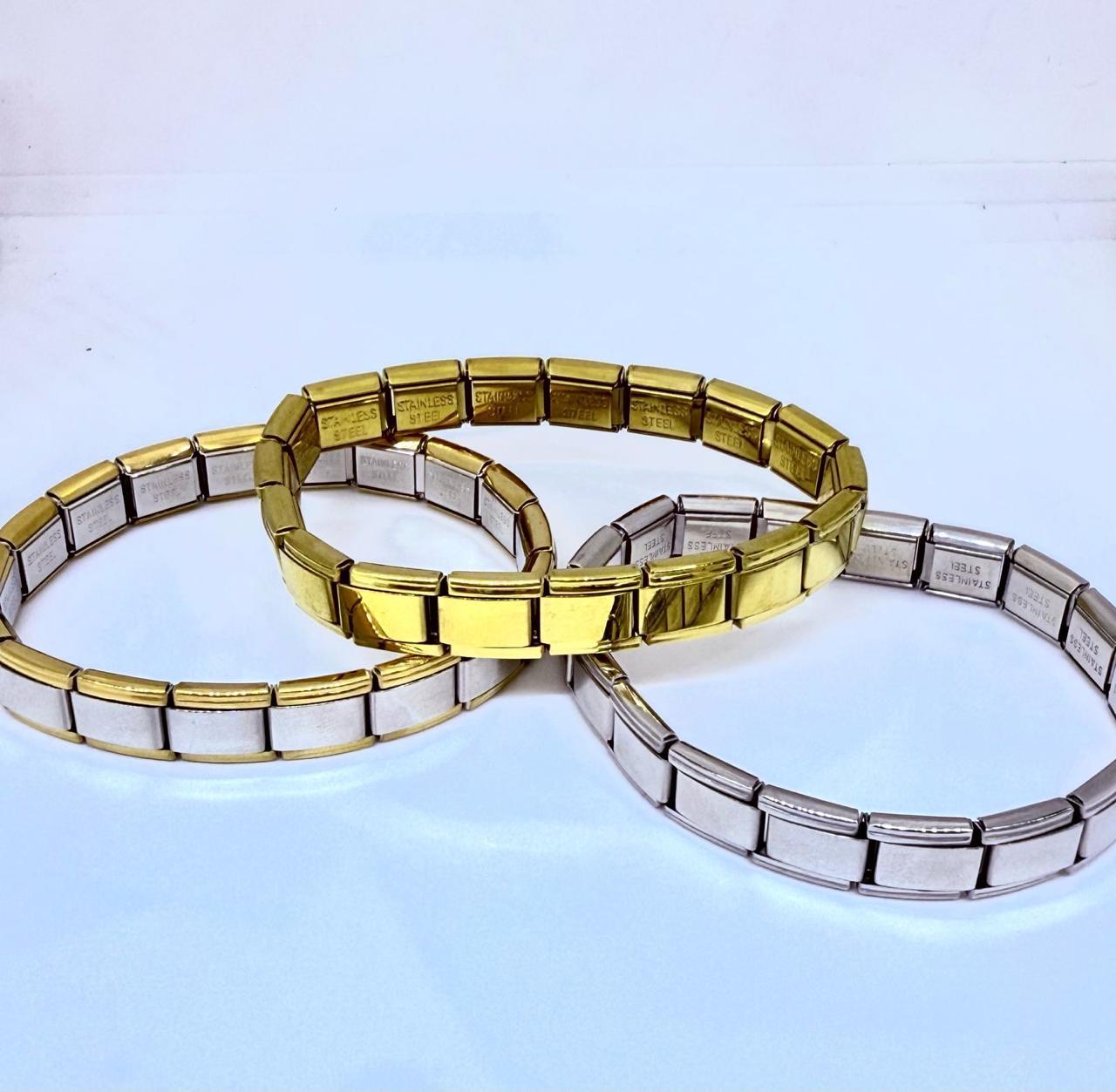 Tres pulseras de acero inoxidable en color dorado y plateado dispuestas sobre una superficie blanca. Tres pulseras de acero inoxidable en color dorado y plateado dispuestas sobre una superficie blanca.