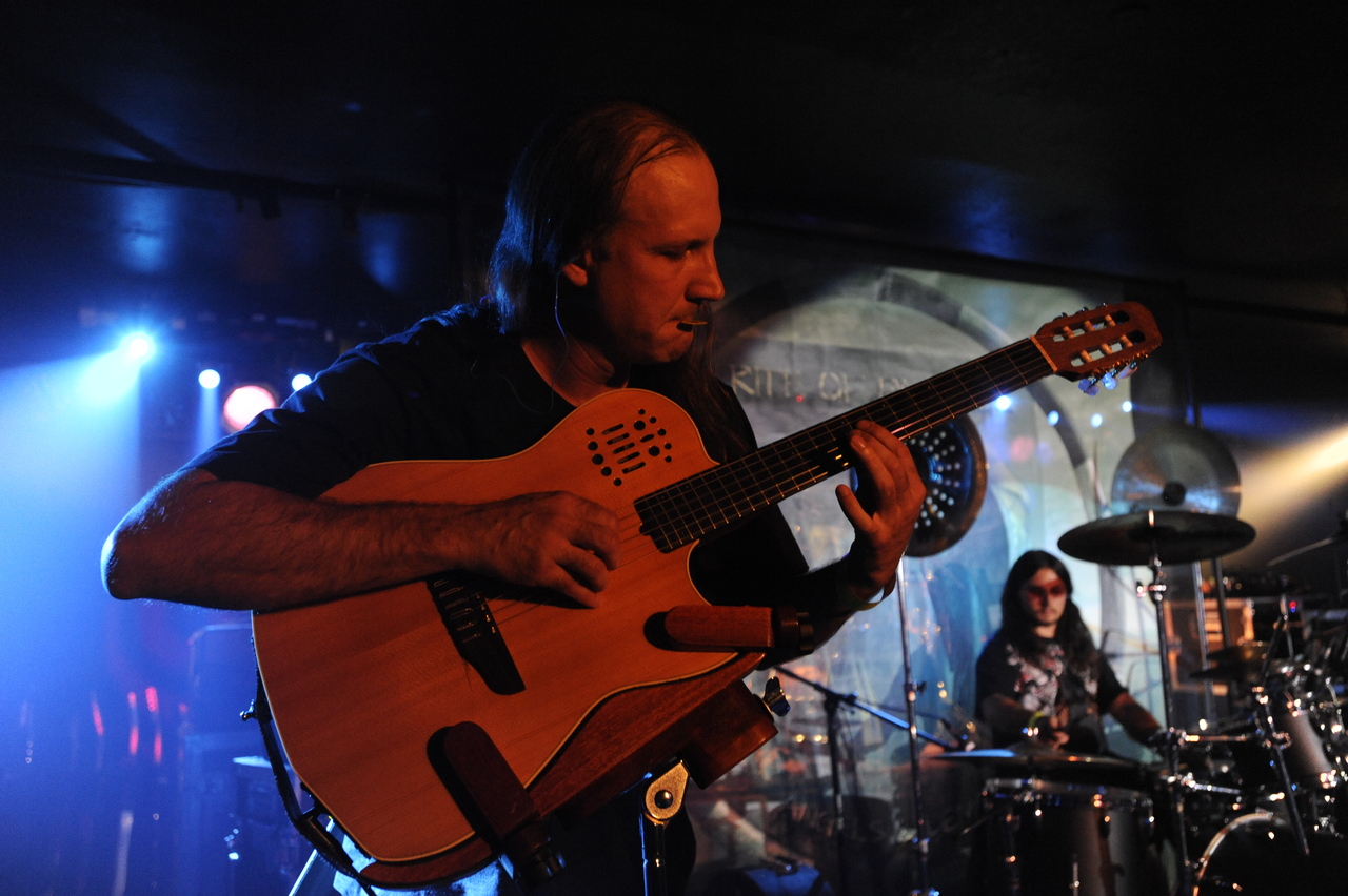 Rock band performing on stage with guitars, drums, and microphones under colorful stage lights.