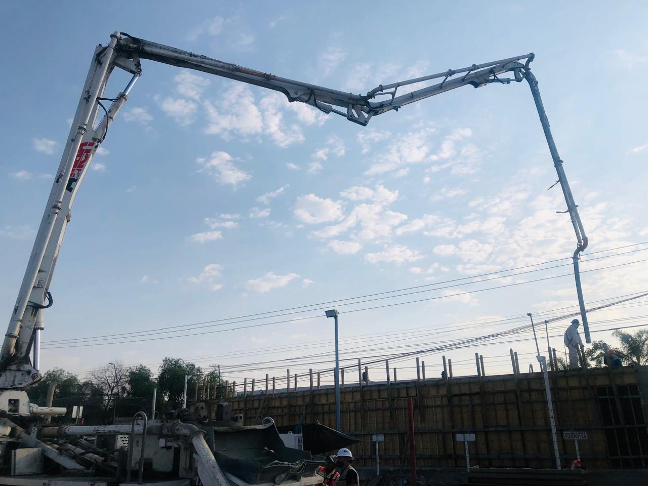 Moderno vestíbulo con sofás amarillos y plantas en macetas, rodeado de ventanales que ofrecen vistas urbanas.
