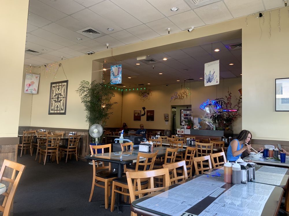 Purple taro bubble tea with boba pearls and a purple straw in a clear plastic cup.