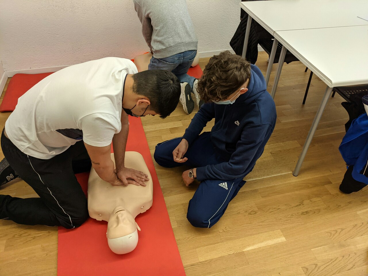 Red AED defibrillator kit on a table in a medical facility with blurred shelves in background.